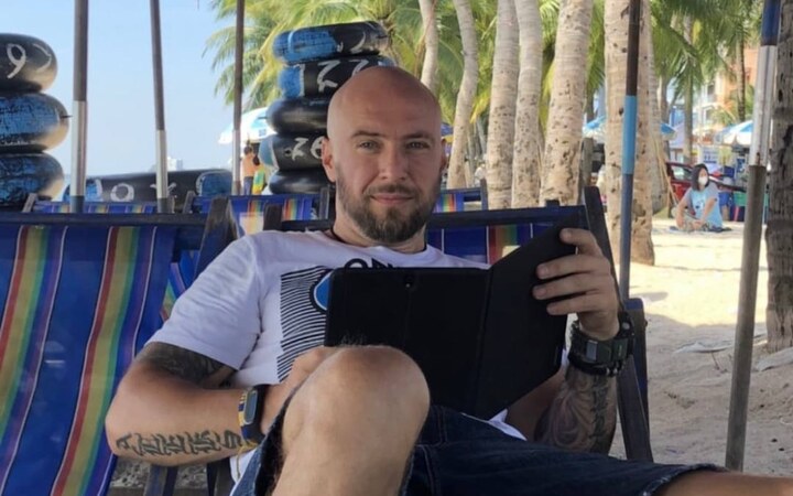 Алексей с планшетом в шезлонге на пляже под пальмами